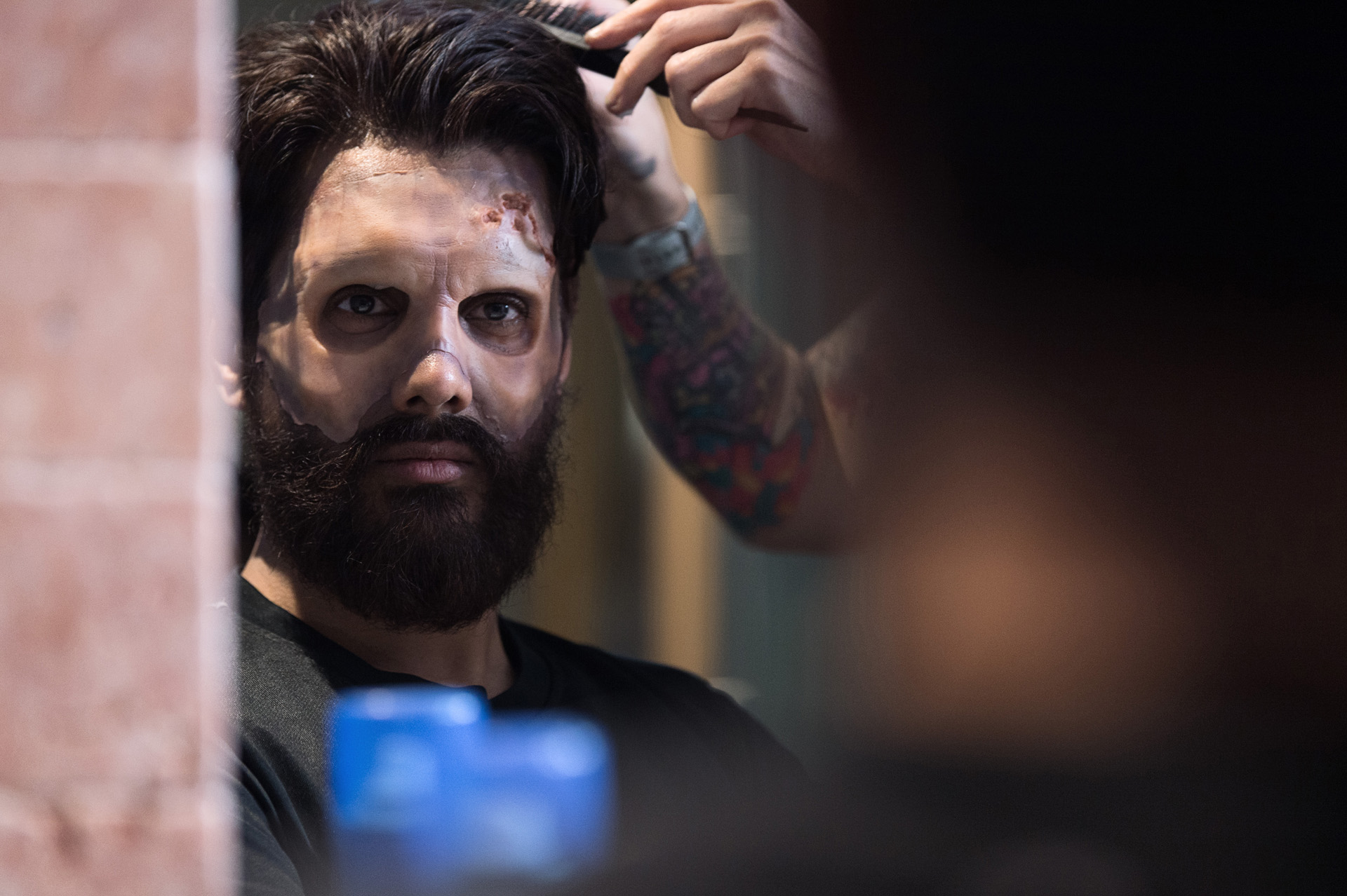 An artist finishing the hair of a performer in full zombie makeup