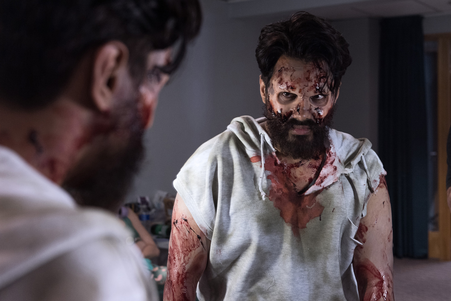 Two performers in torn bloodied costumes and zombie makeup waiting backstage