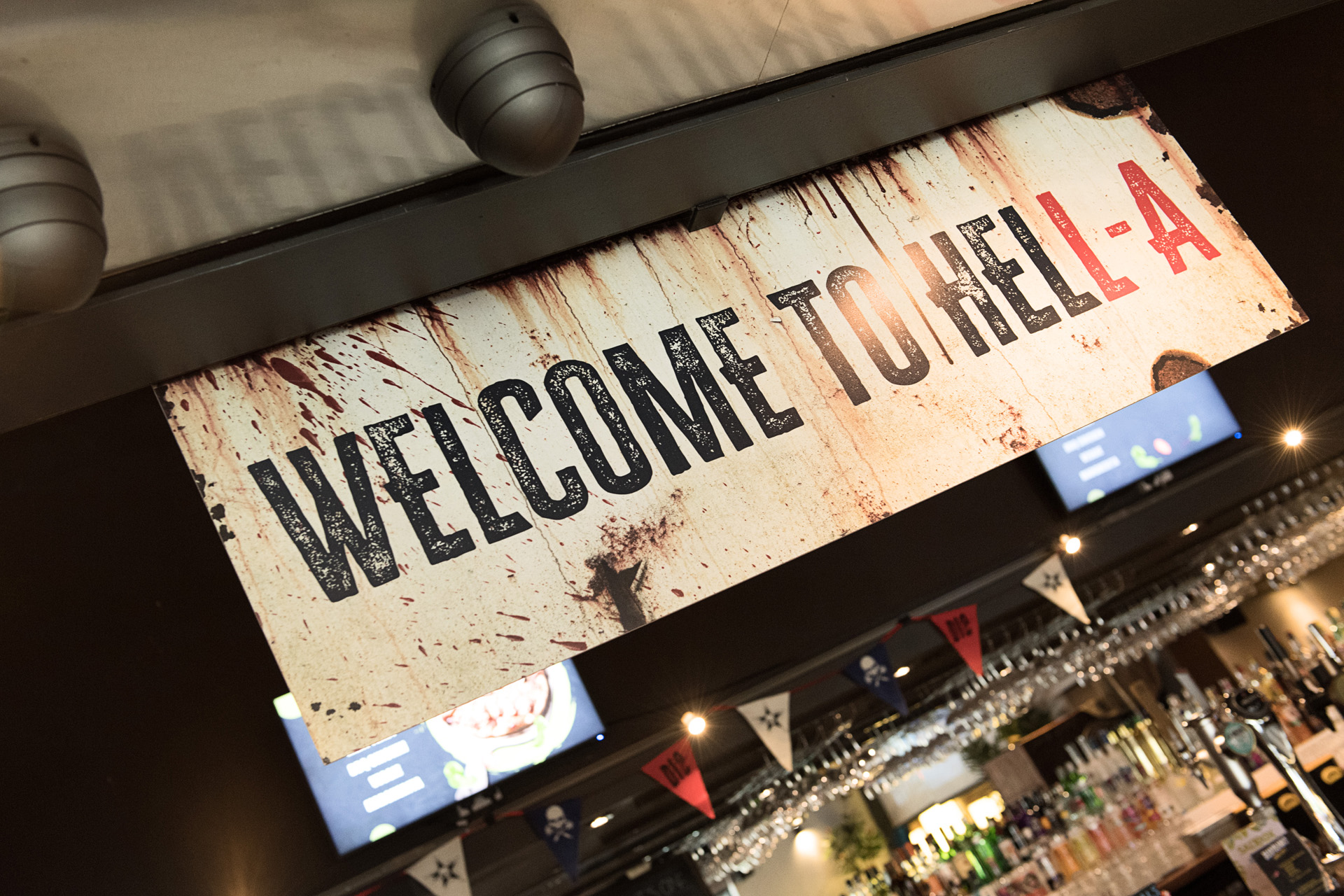 A weathered Welcome to Hell A sign hanging above a bar at a themed launch