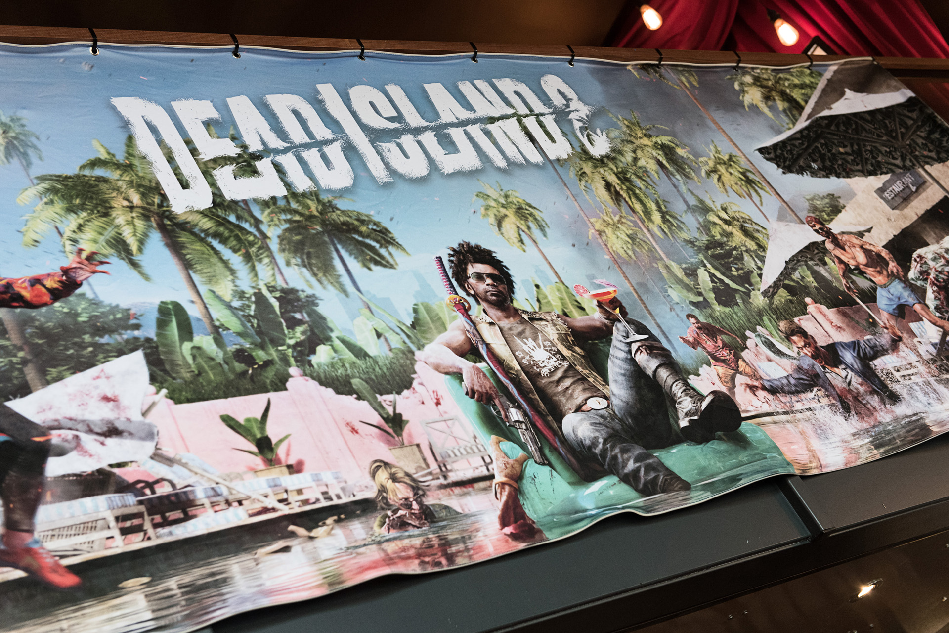 A large game artwork banner mounted above a stage at an internal launch event