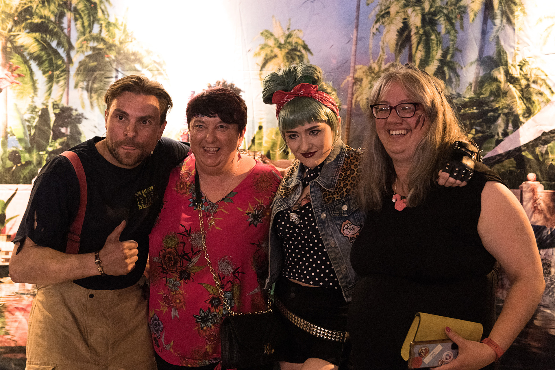 Four guests posing together in front of a tropical backdrop at a launch party
