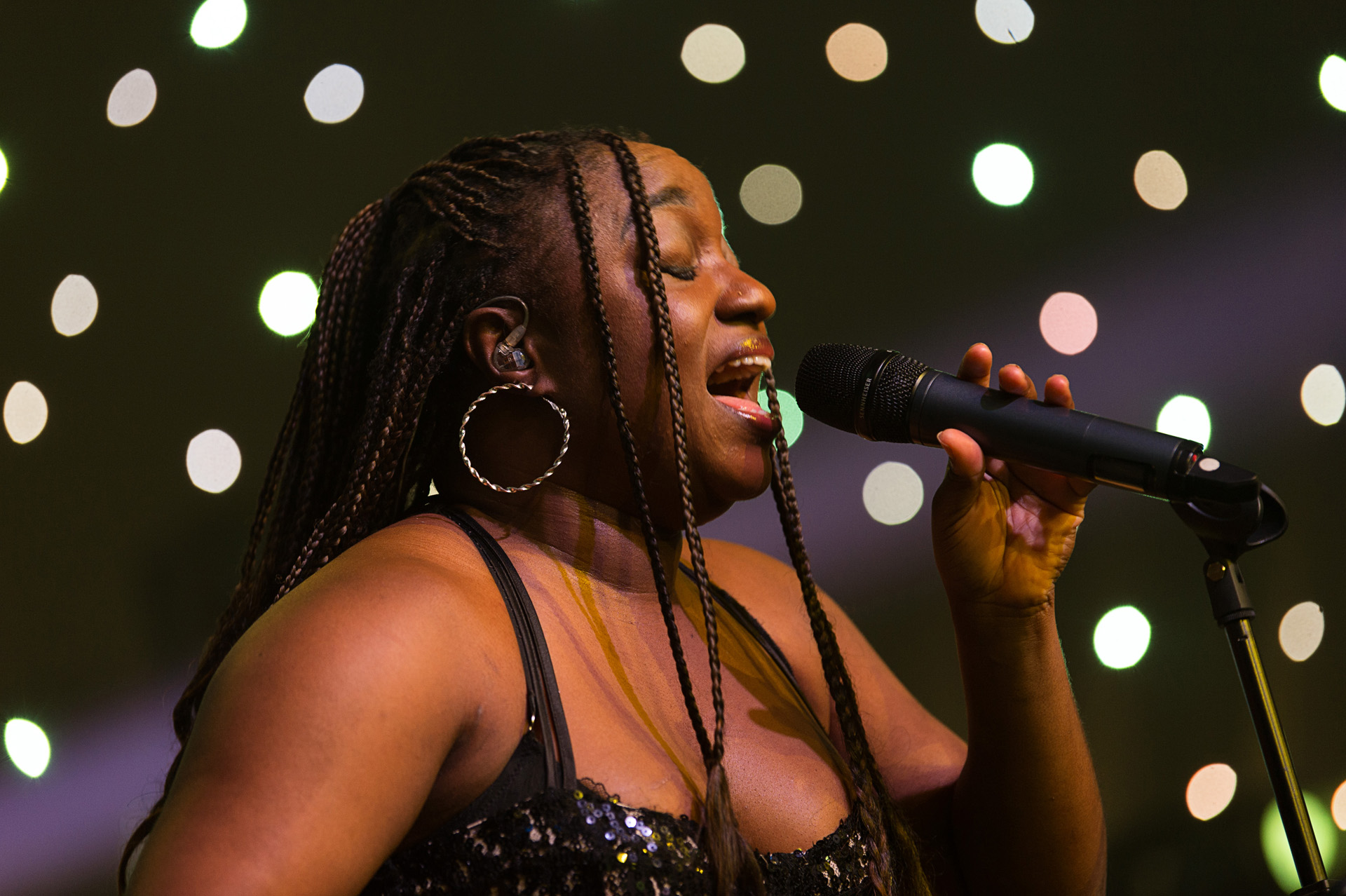 A singer performing into a microphone in front of a wall of small lights