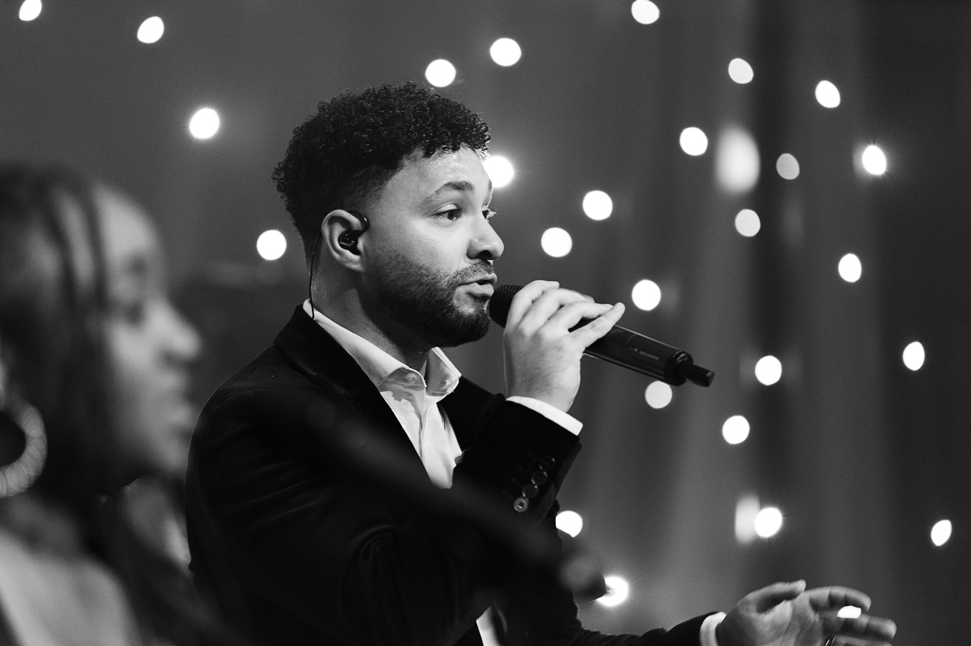 A singer performing with a backing vocalist in front of a starlit curtain