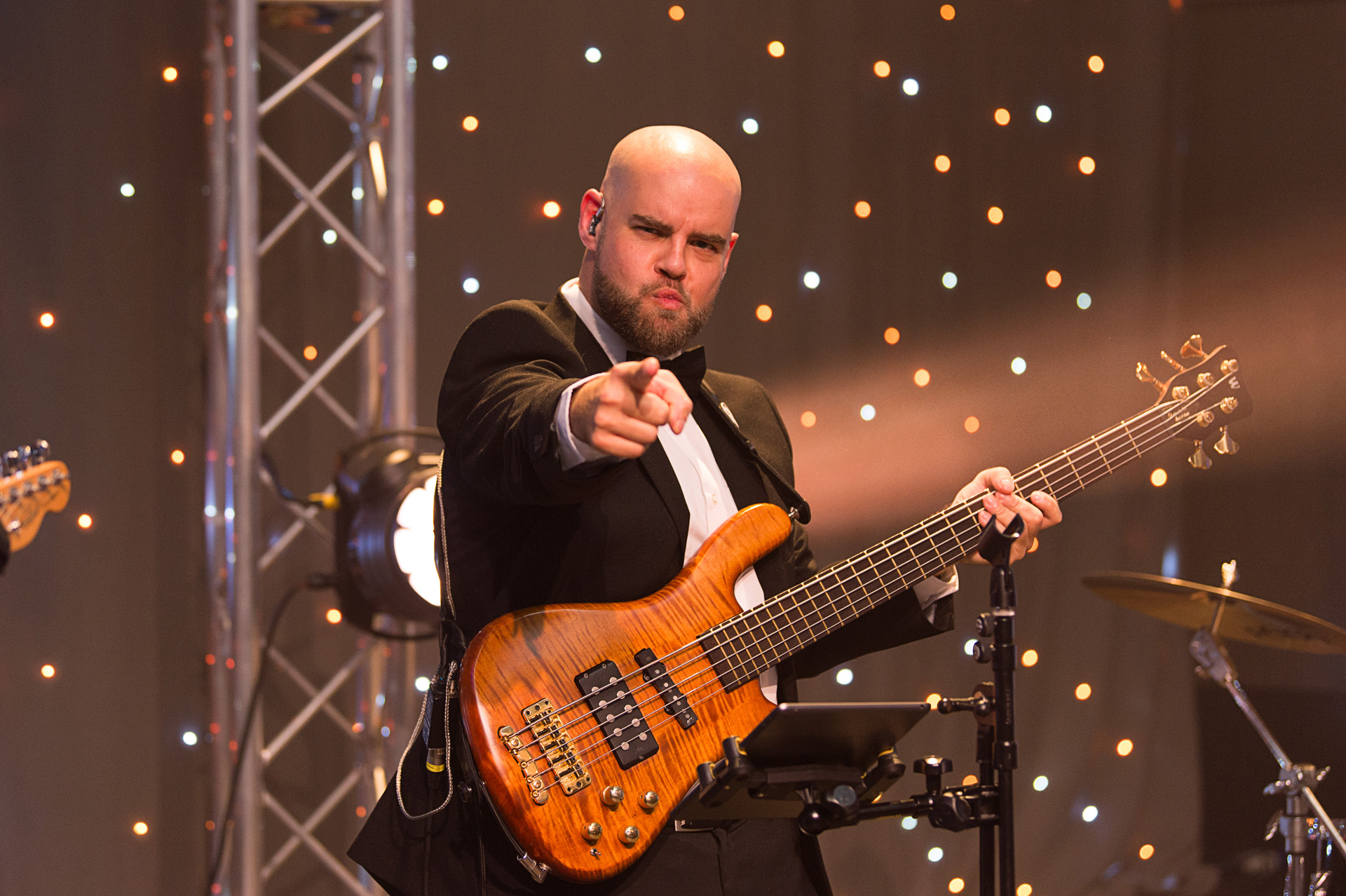 A bass player pointing towards the crowd while performing on stage