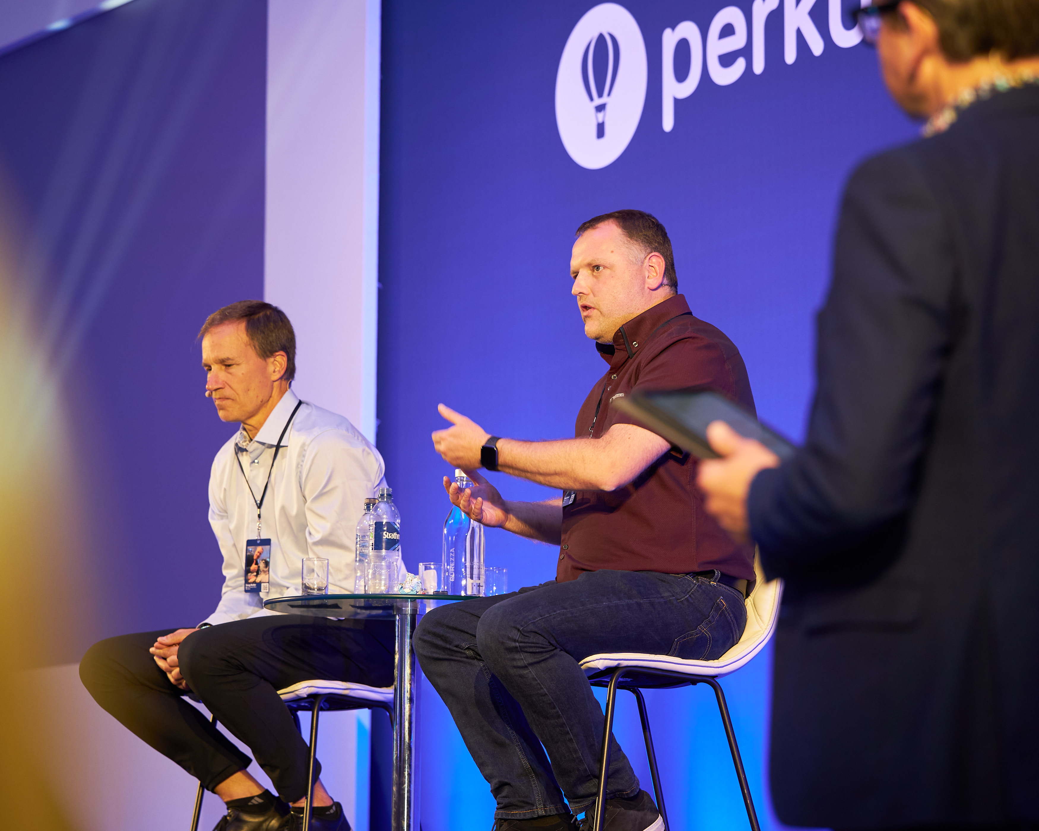 Two leaders in conversation on stage stools during a company all-hands session