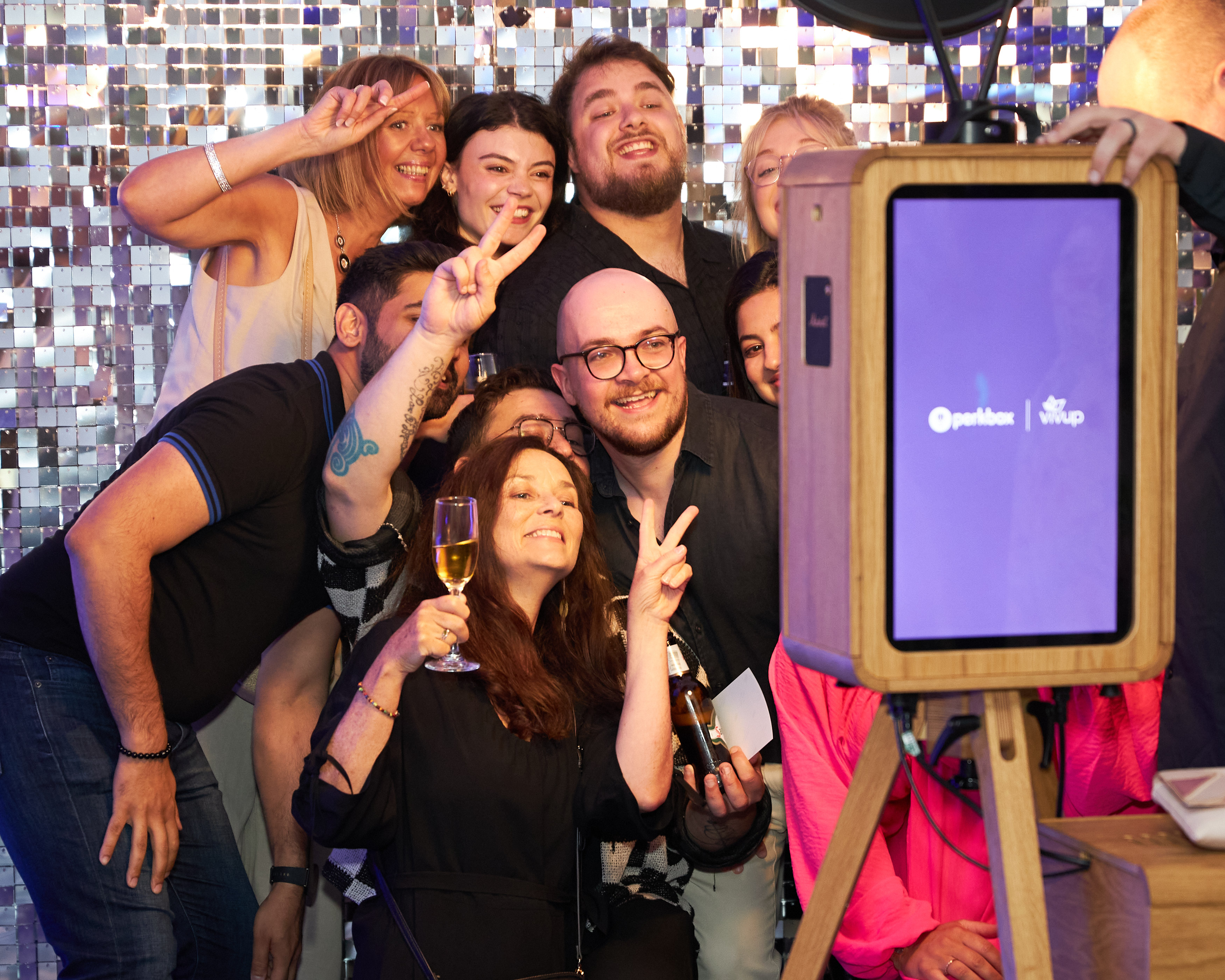 A group of colleagues posing for a photo booth camera against a mirrored backdrop