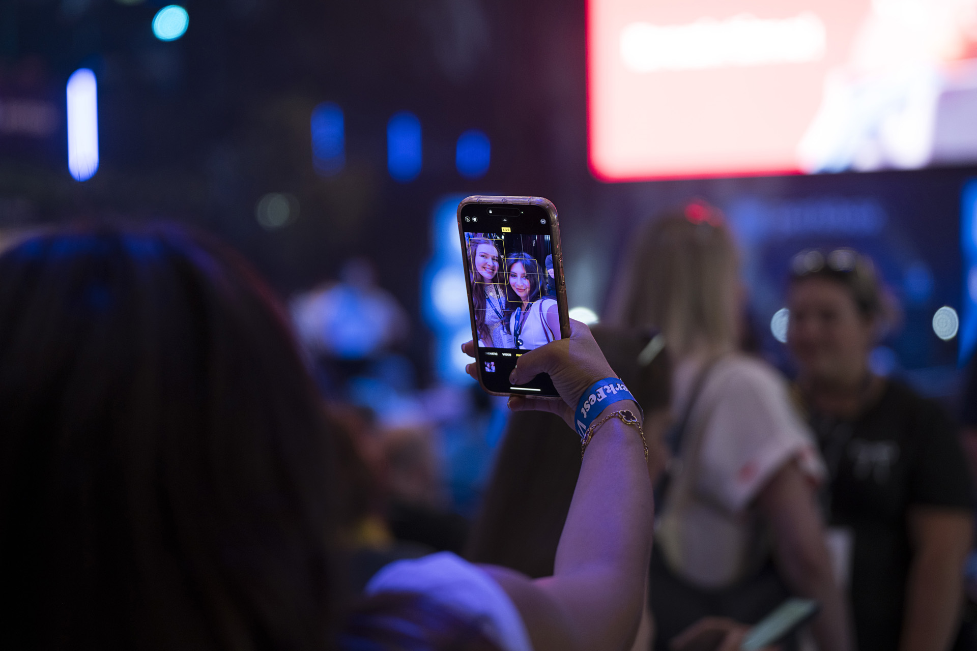 An attendee holding up a phone to photograph two friends at an indoor event