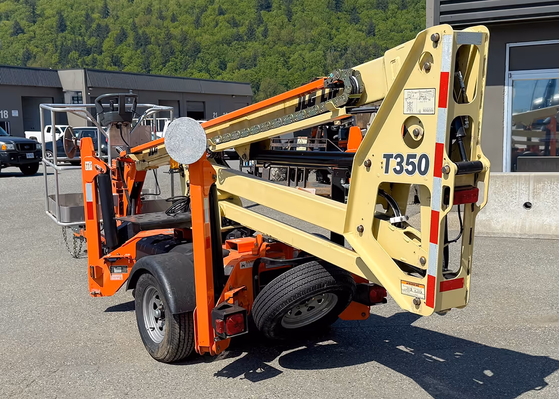 Rear-side view of 2020 JLG T350 boom lift showing folded boom arm and tow hitch assembly