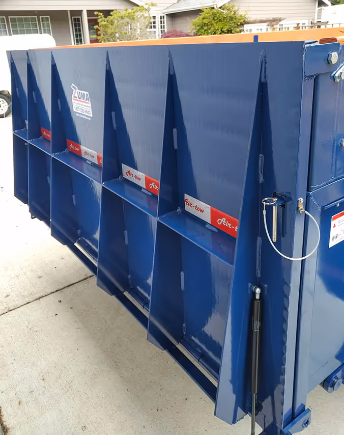 Detailed side view of the blue dump trailer's heavy-duty reinforced steel walls and gate latch system.