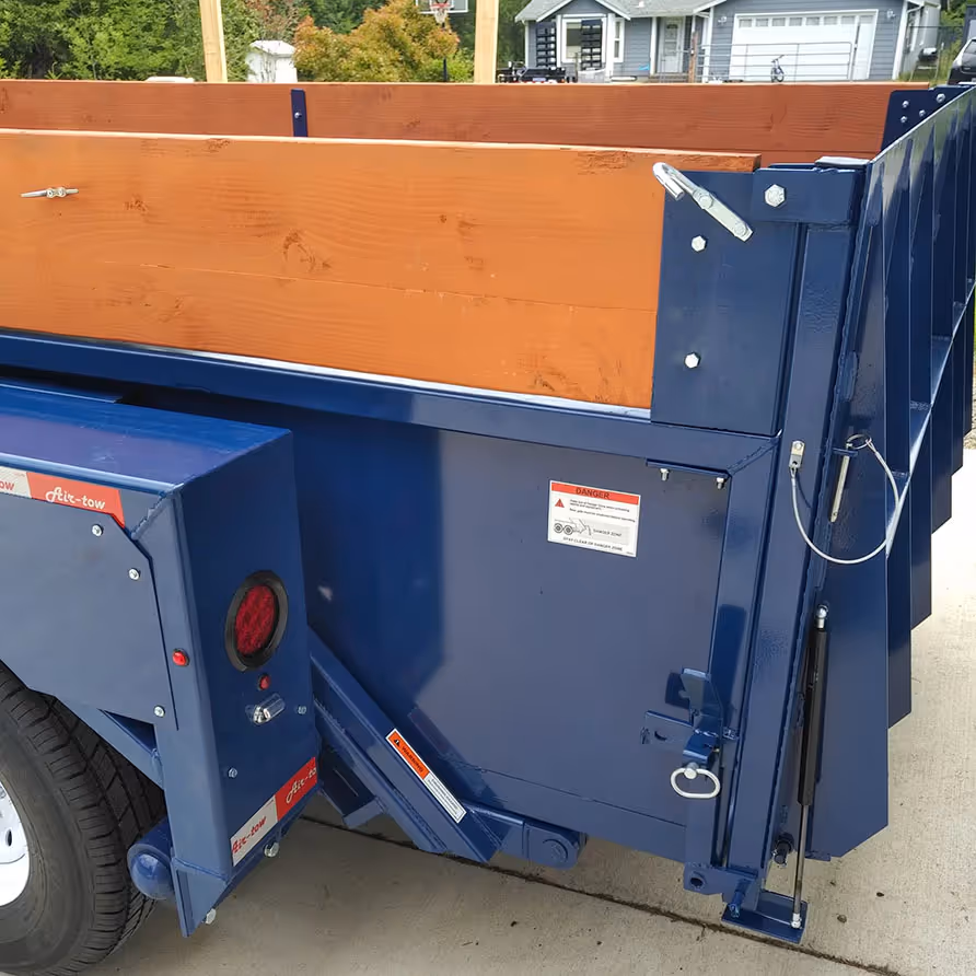 Close-up of the rear barn door gate on the dump trailer, showing the latch pin and hydraulic assist.