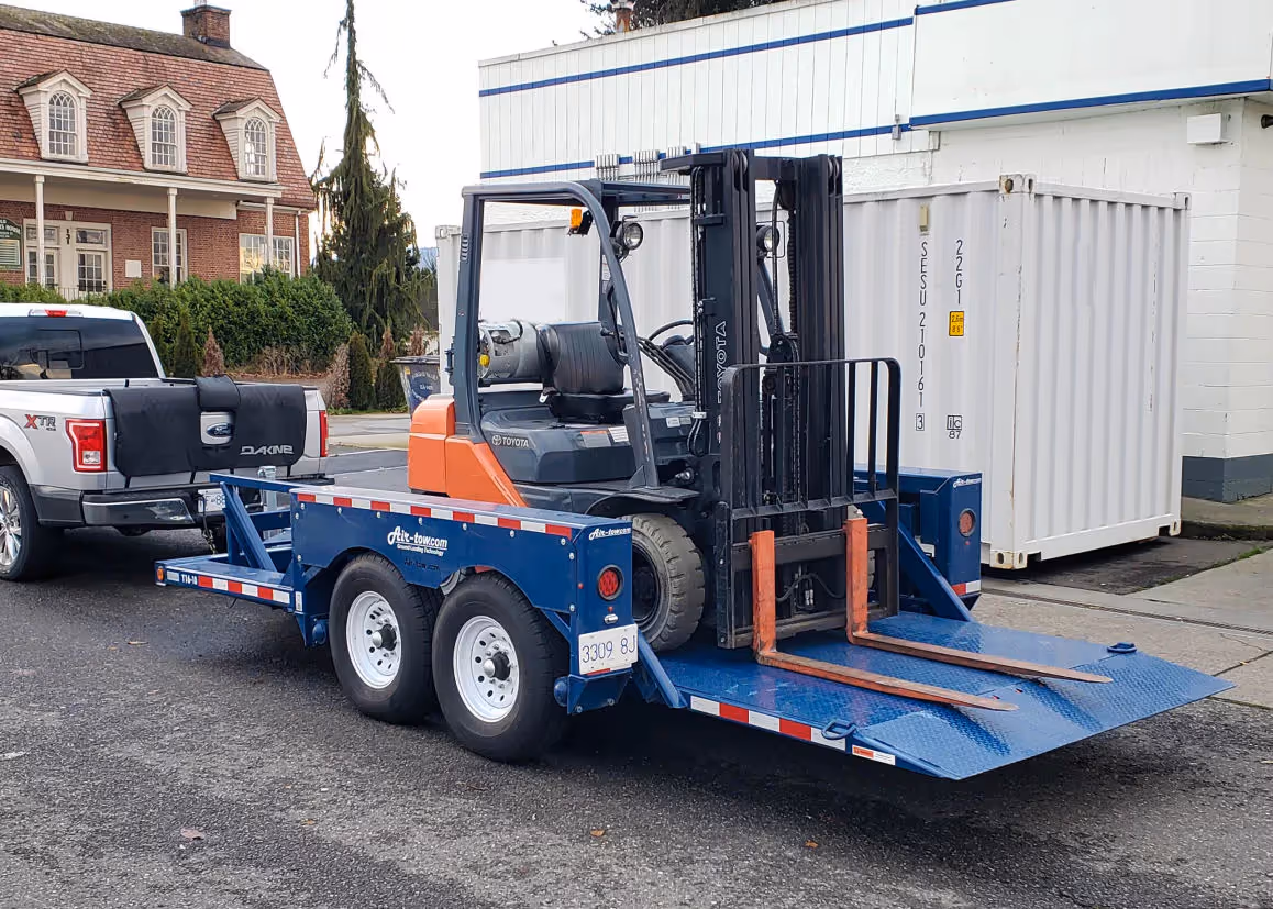 Airtow T16-12 trailer hauling forklift on blue ramp in Canada