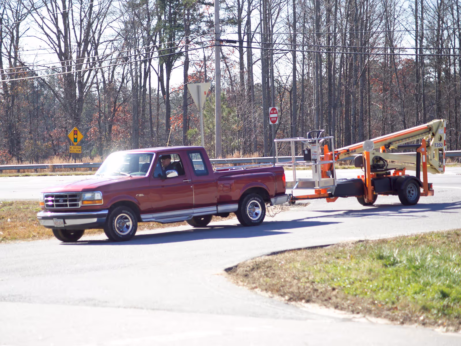 JLG T350 being towed by red pickup truck on road in Canada