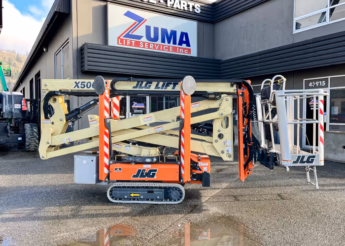 Side view of a JLG X500AJ articulating crawler boom lift in its stowed position outside the Zuma Service-Parts building.