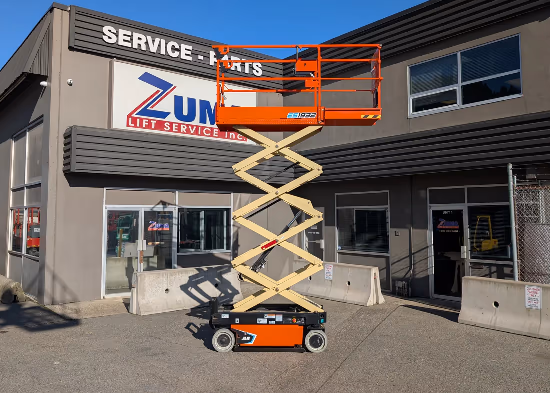 JLG ES1932 electric scissor lift fully elevated in front of building in Canada