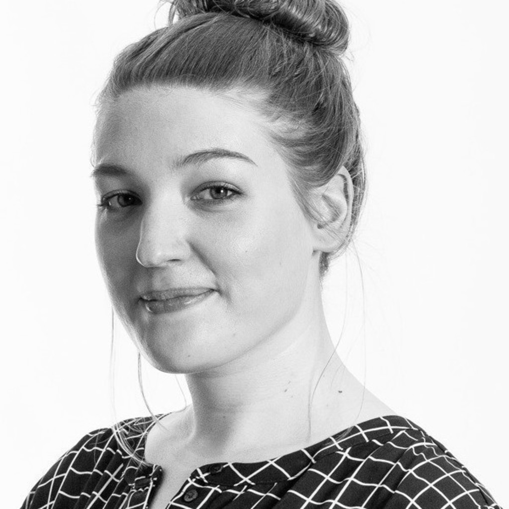 Black and white portrait of a young woman with hair in a bun wearing a patterned shirt, smiling slightly.