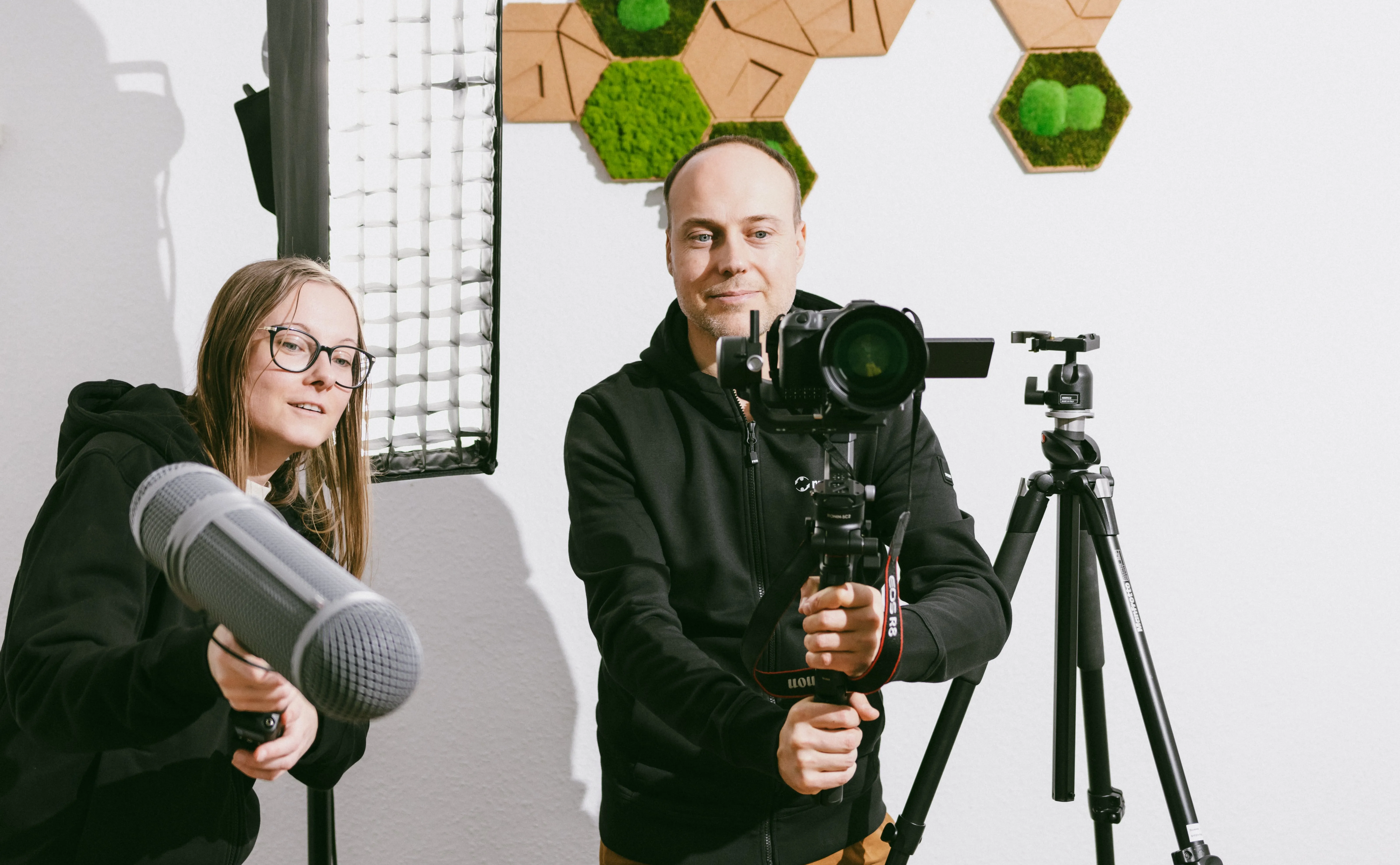 Zwei Personen mit Kamera- und Tonequipment beim Videodreh im Studio