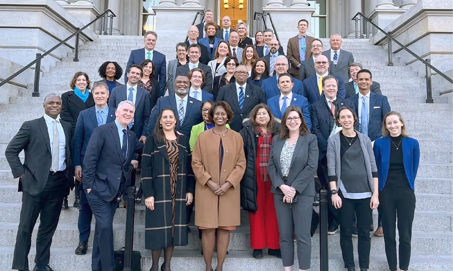 large group of business professionals stand posing for camera on steps of government building