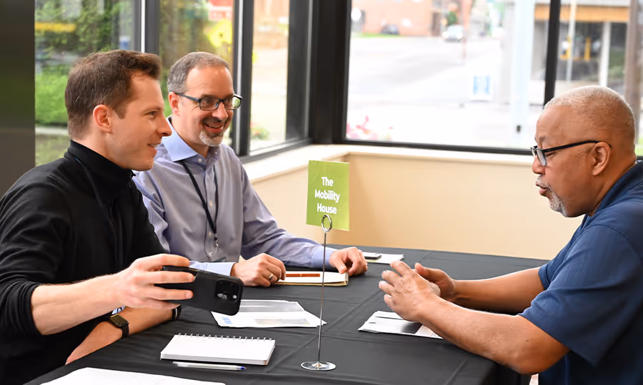 three business professionals sit at a table chatting happily during networking event