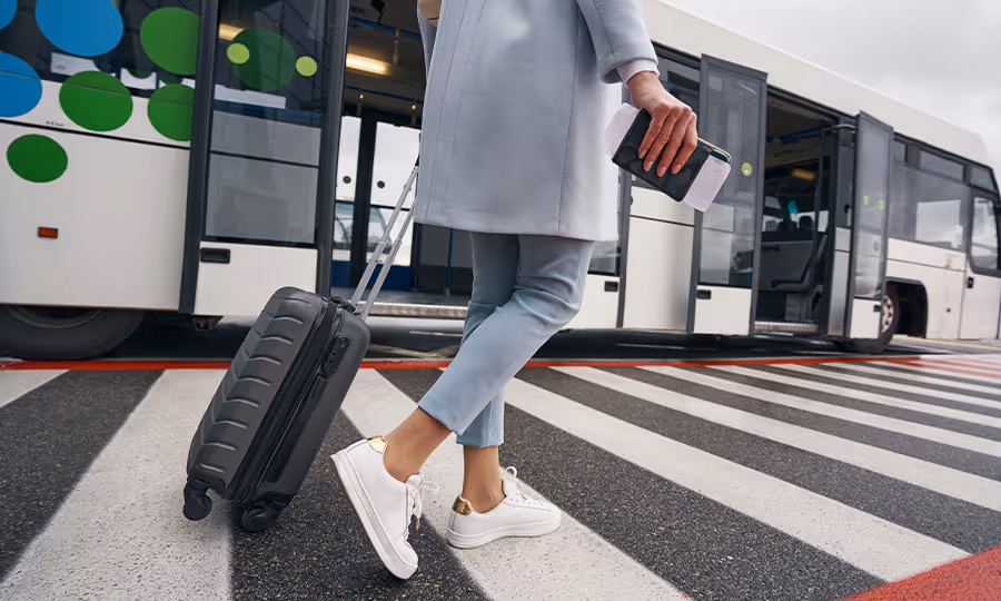woman with suitcase walking in crosswalk with shuttle train in background