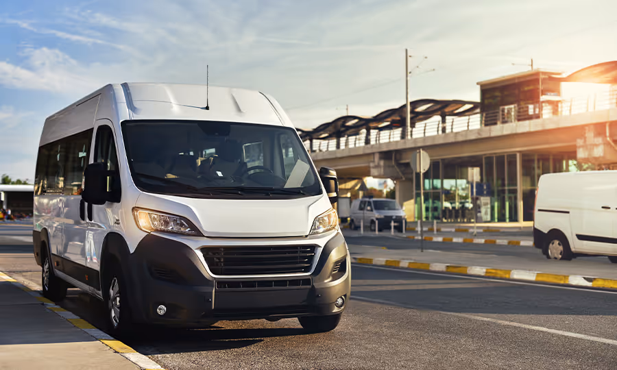 white shuttle van parked outside airport
