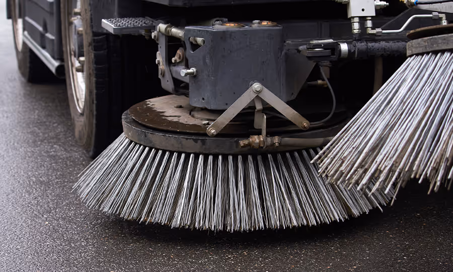 close up of street sweeper brushes on pavement