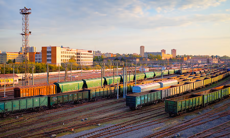 train yard with numerous shipping containers parked and city in background