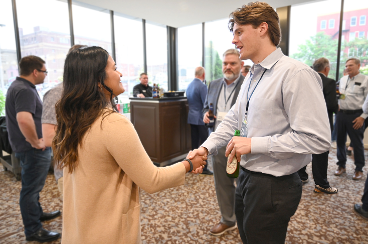 Two business professionals shake hands at cocktail networking event