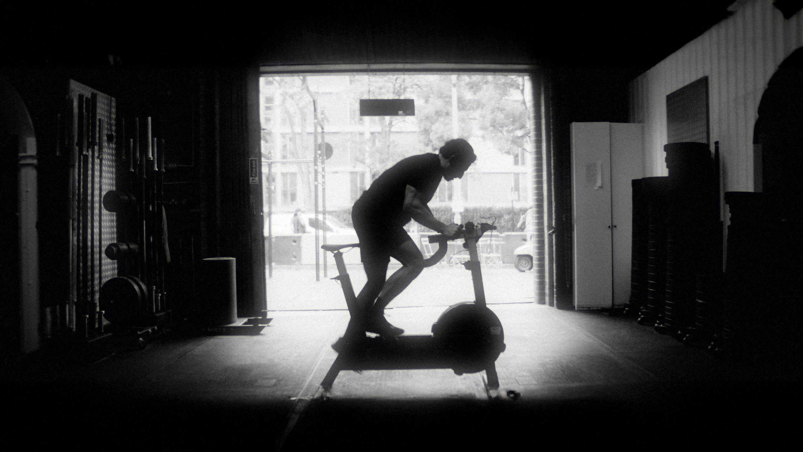 Silhouette of a man on an exercise bike in a gym doorway