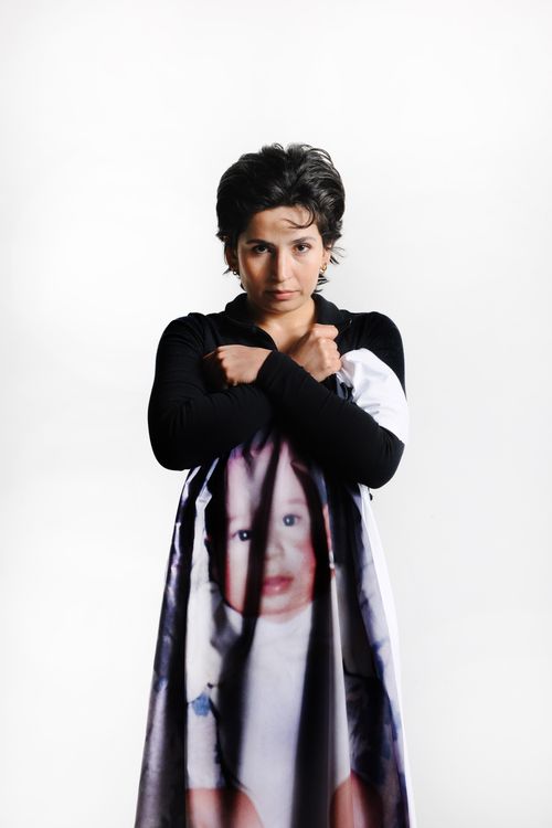 Een vrouw houdt en doek met een babyfoto stevig tegen zich aan