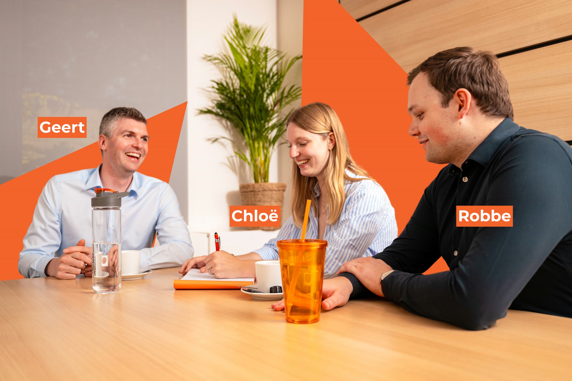 Geert, Chloë en Robbe lachen tijdens een overlegmoment over accountancy aan een houten vergadertafel.