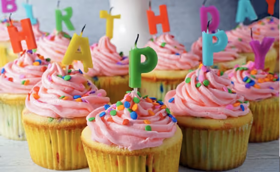 Happy Birthday cupcakes with colorful letter candles and sprinkles
