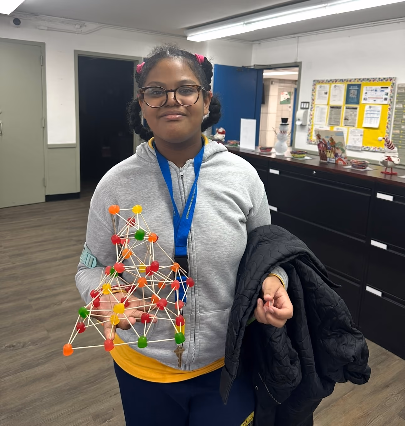 Student holding STEM model and smiling