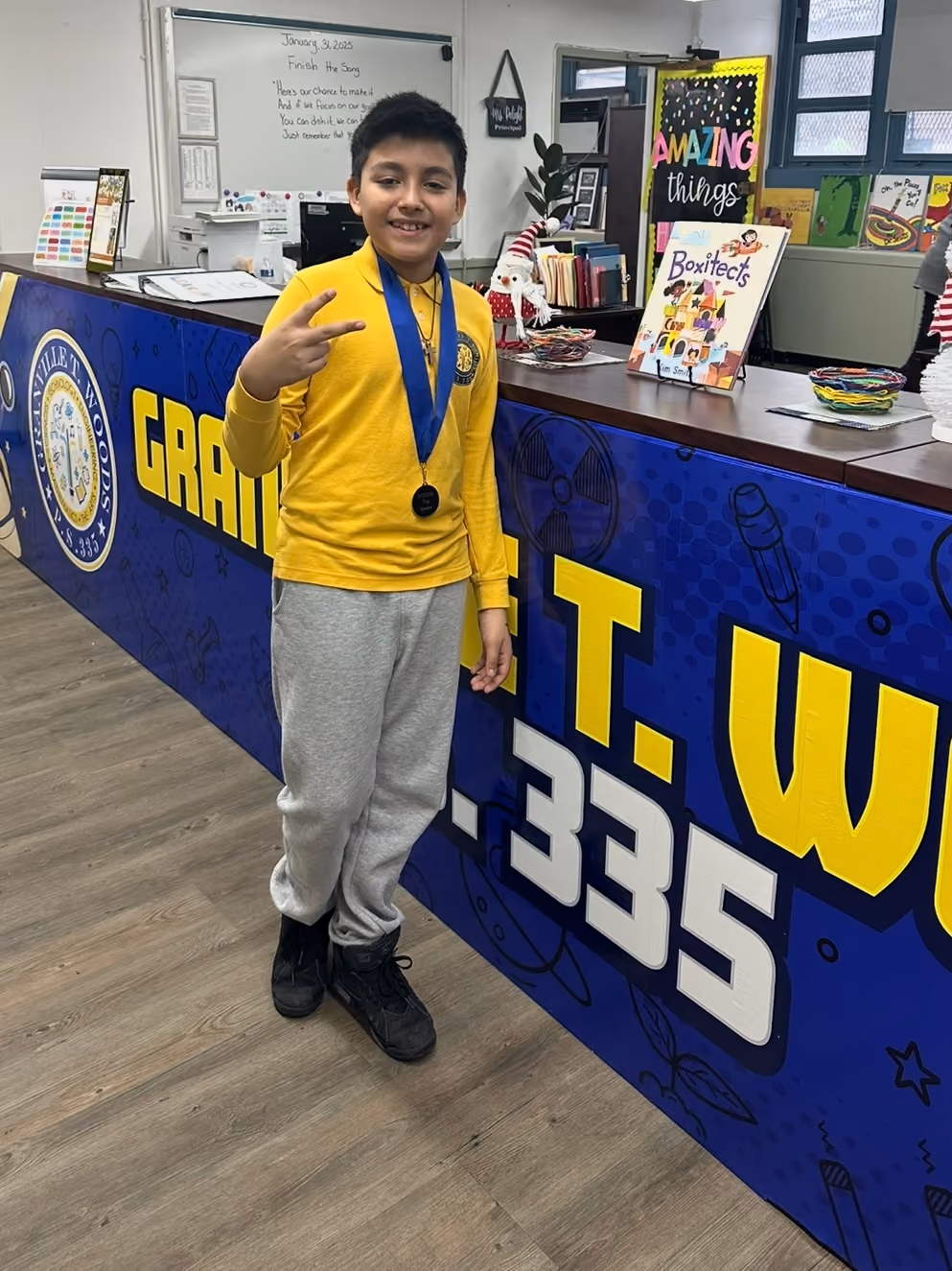 Student wearing medal standing at school front desk