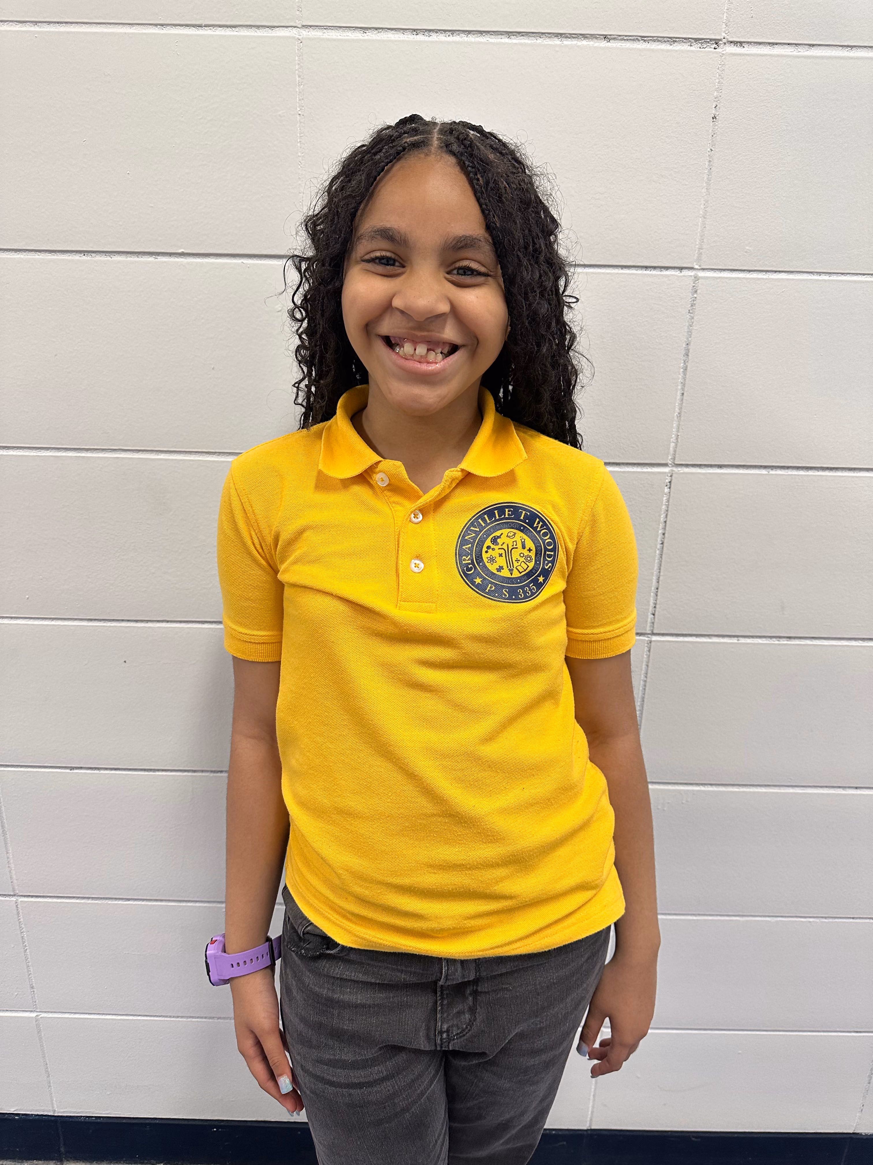 Smiling PS 335 student in yellow school uniform polo shirt