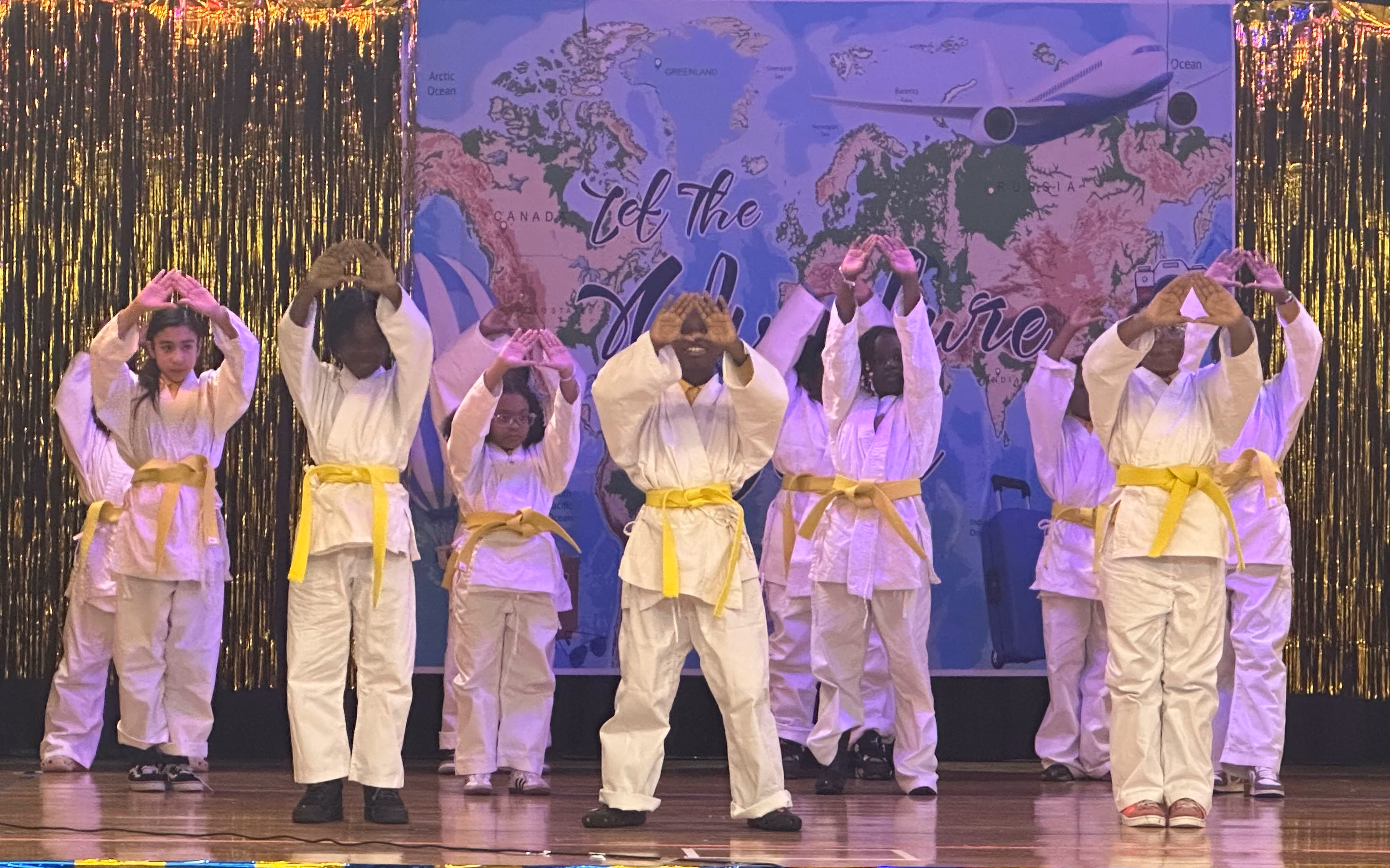 Students in white martial arts uniforms performing on stage