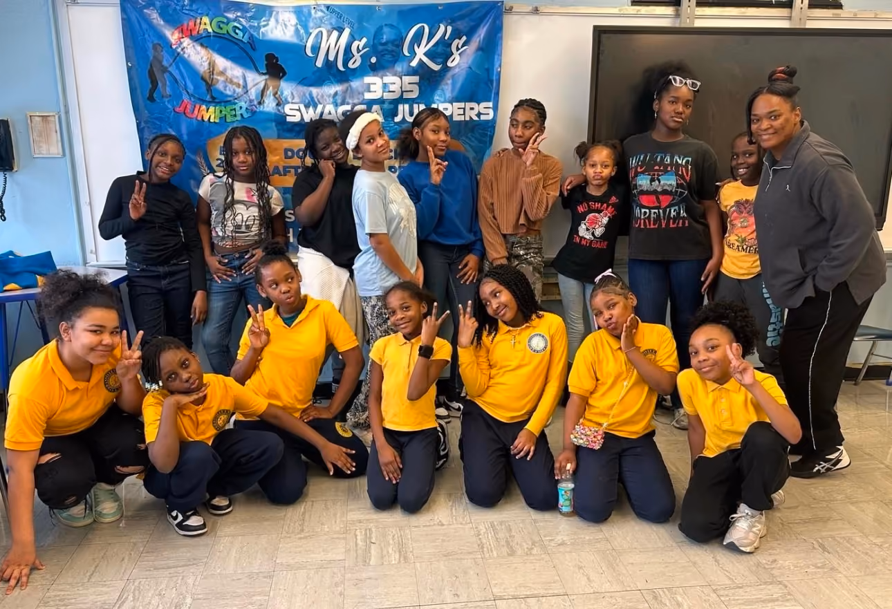 Students and teacher posing with Ms K's Swagga Jumpers double dutch banner
