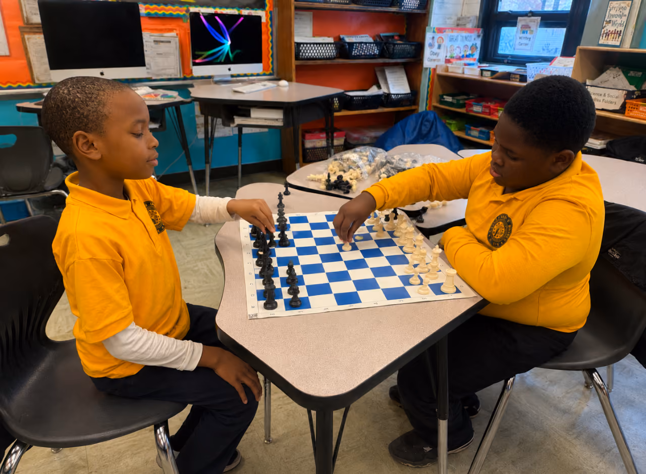 Two students in uniform playing chess together in a classroom