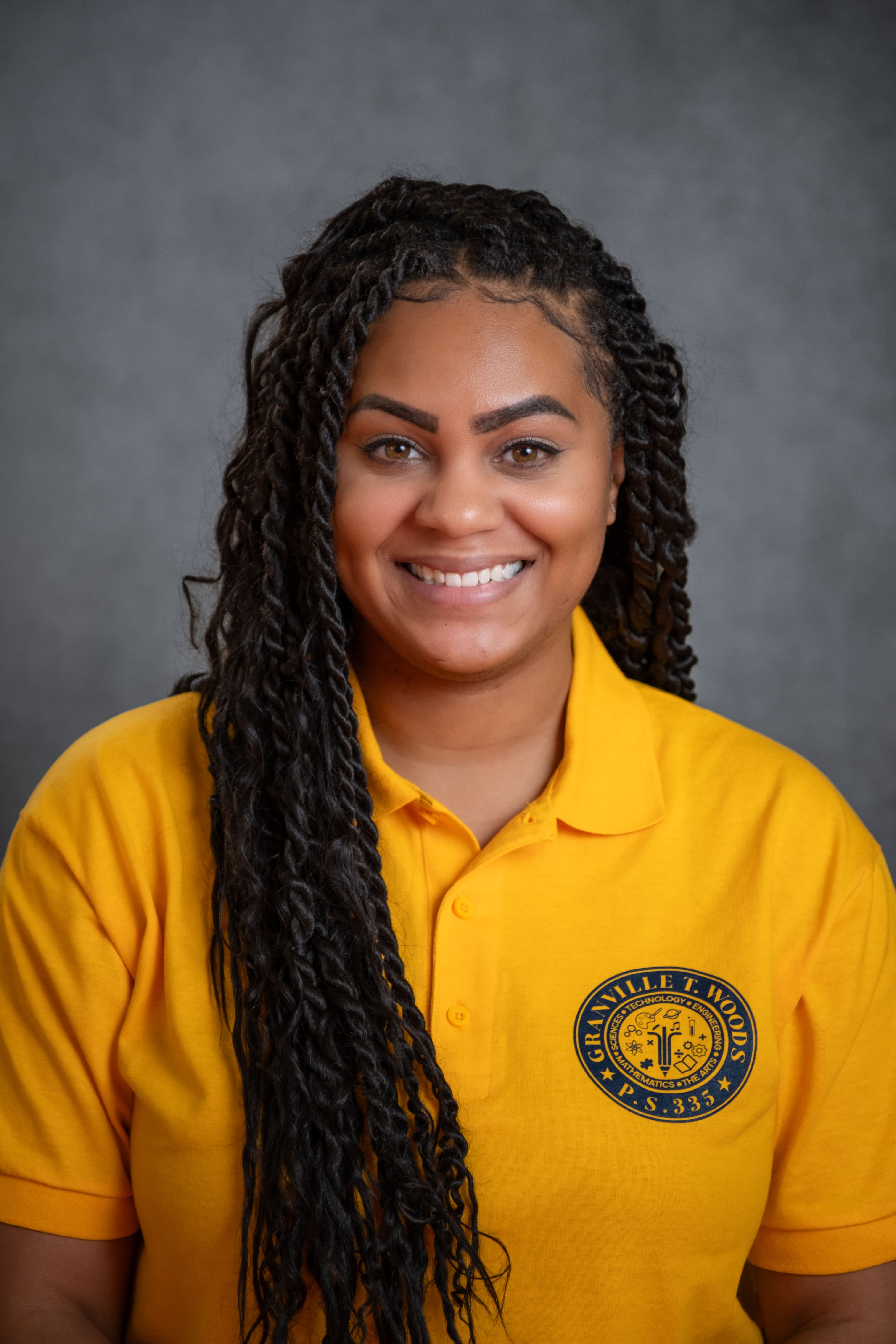 Staff member V. Hoyte smiling in Granville T. Woods PS 335 polo shirt