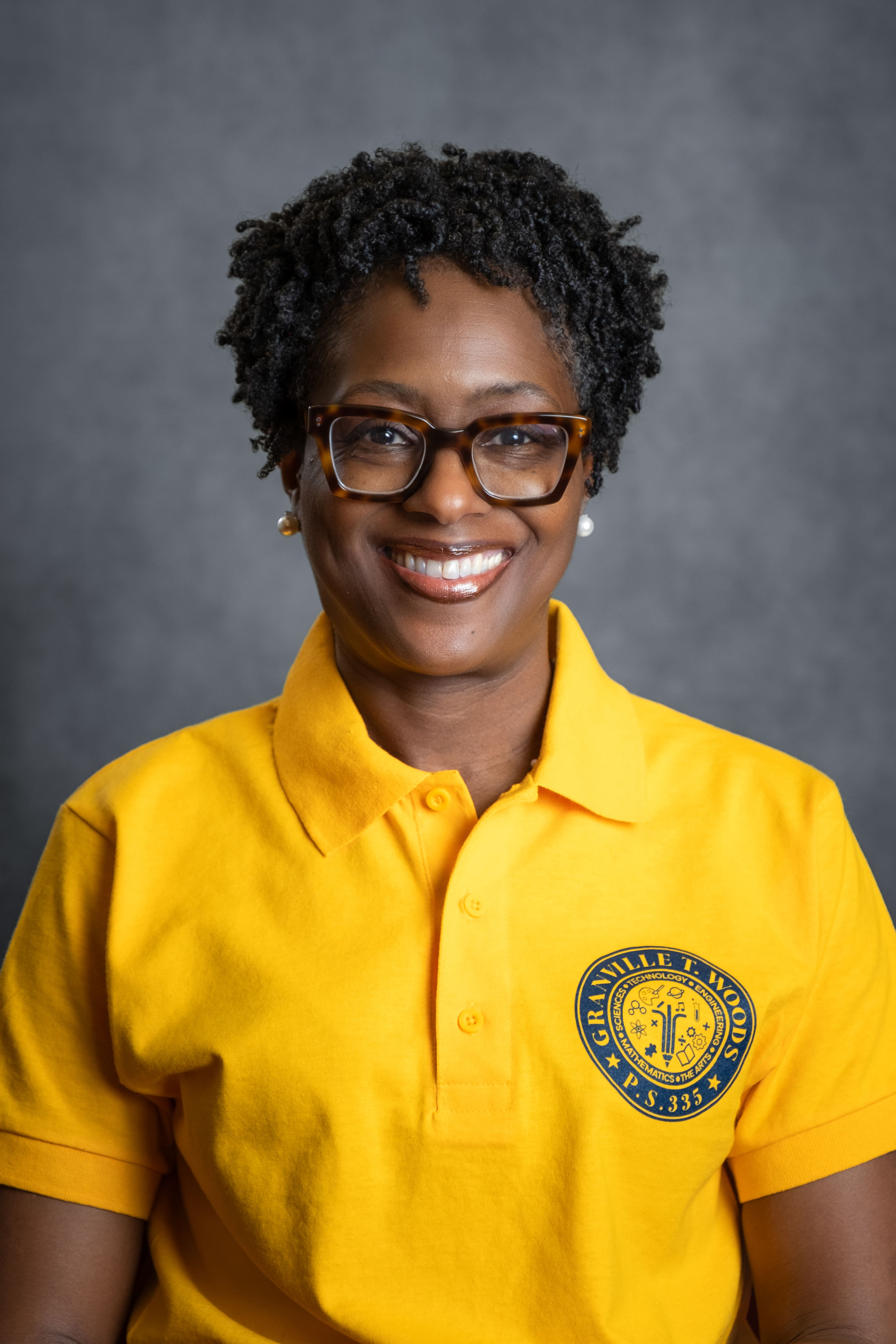 K. Armstead staff member smiling in Granville T. Woods PS 335 polo