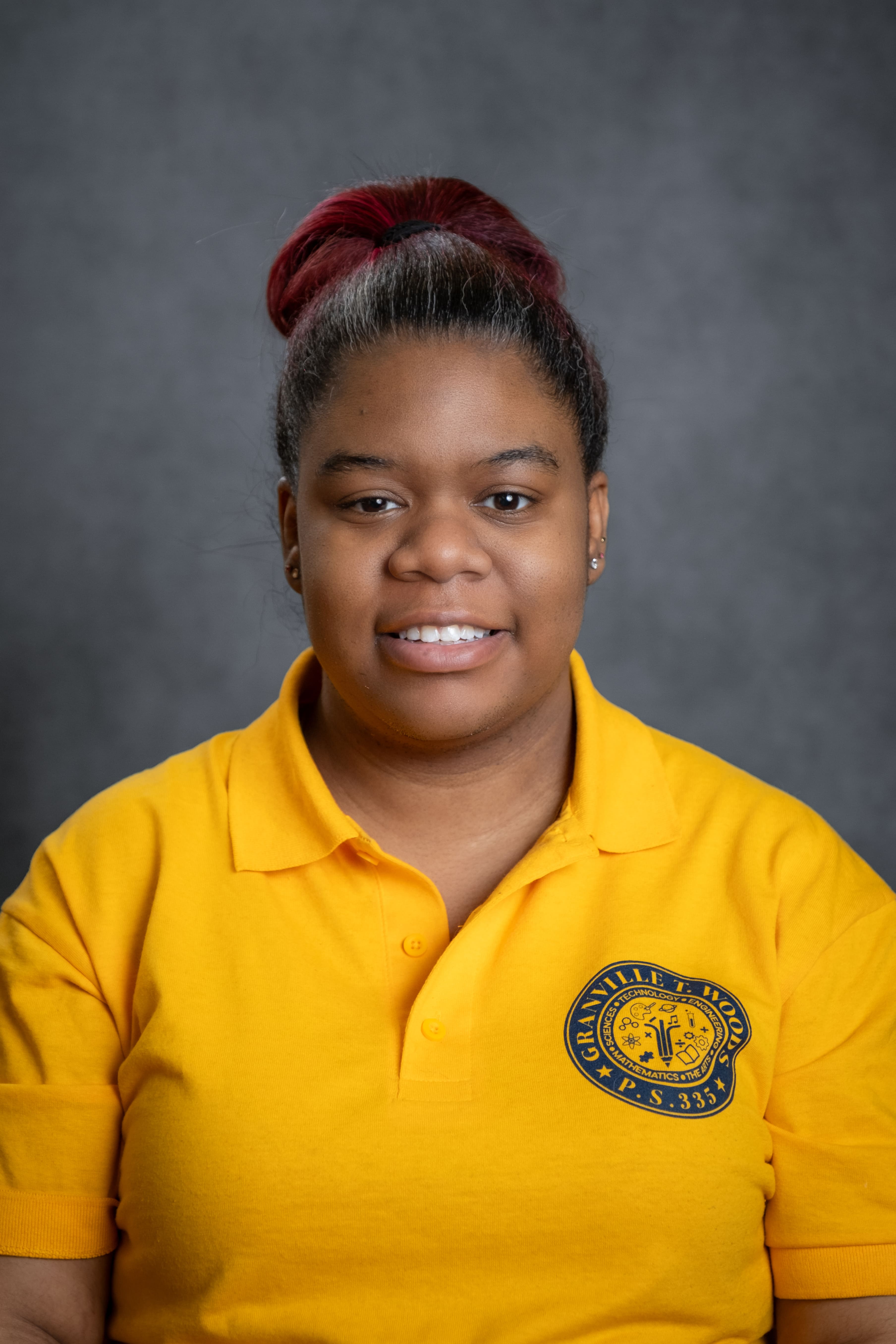 K. Munroe smiling in PS 335 yellow school uniform polo