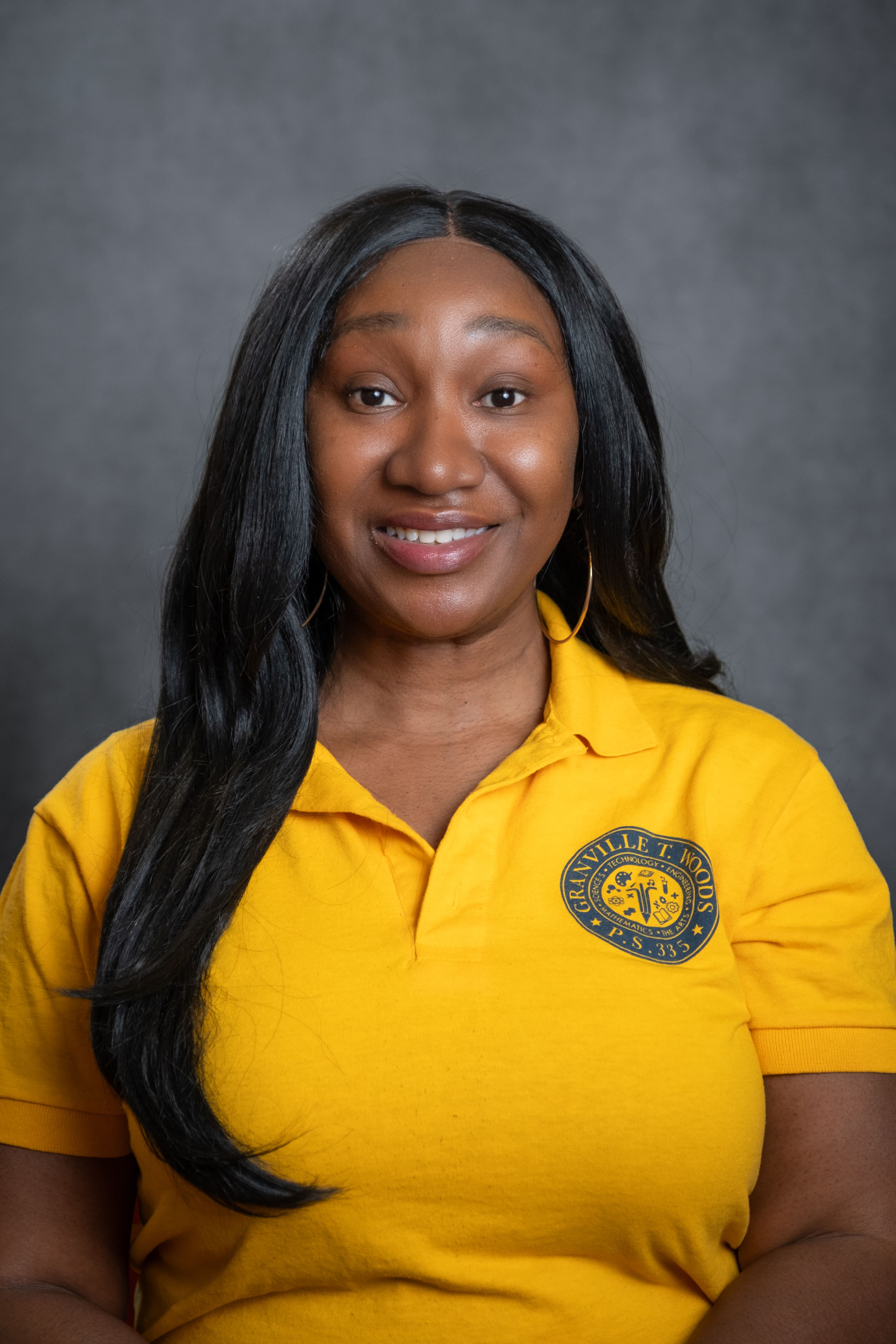 Staff member C. McMillan smiling in Granville T. Woods PS 335 polo