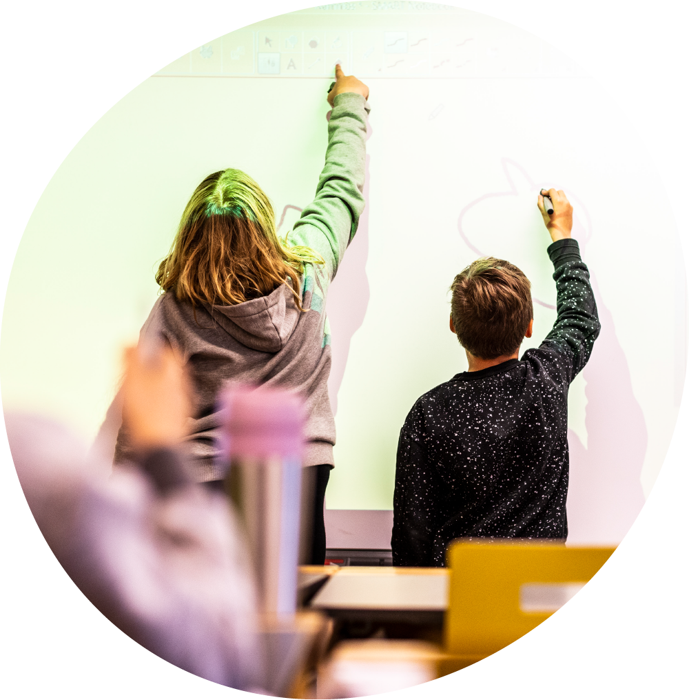 Två elever skriver på en smartboard i ett klassrum.