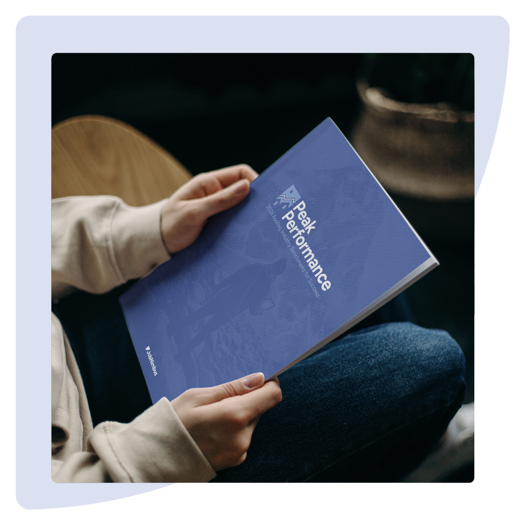 A person holding a report titled "Peak Performance" with the JobNimbus logo on the cover. The report focuses on "2025 Roofing Industry Benchmarks for Success," with a mountain image in the background.