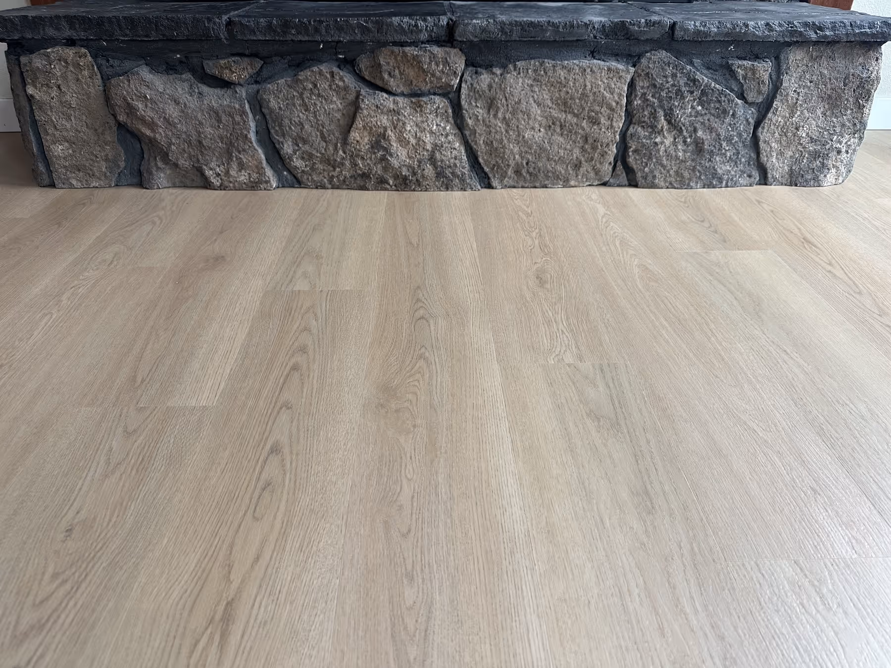 Light LVP textured flooring with a stone hearth.