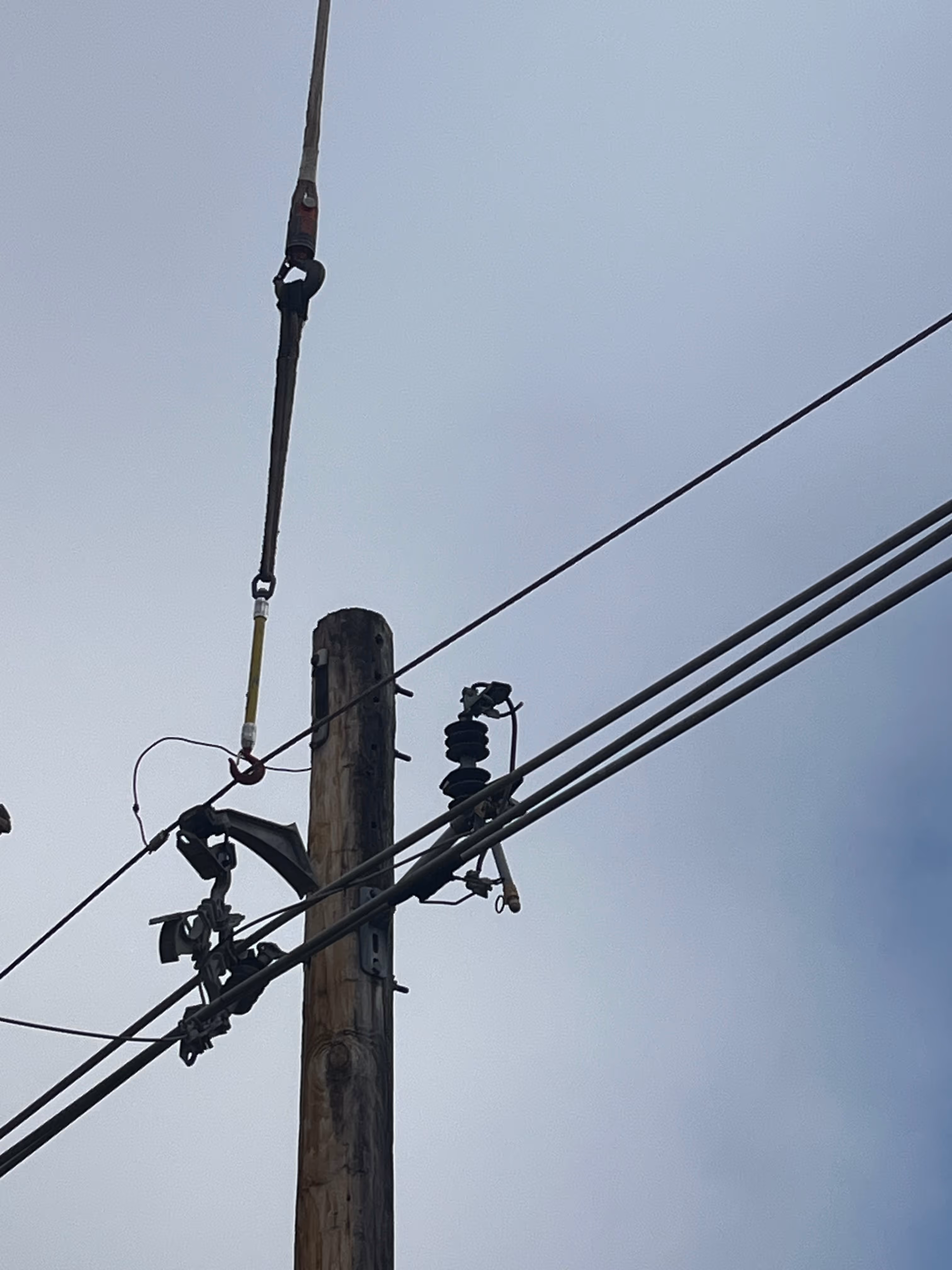 A temporary cable holds up a power wire next to a broken Hendrix bracket.