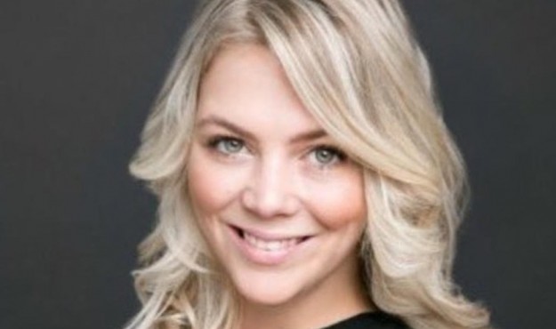 Smiling woman with long blonde hair against a dark background.
