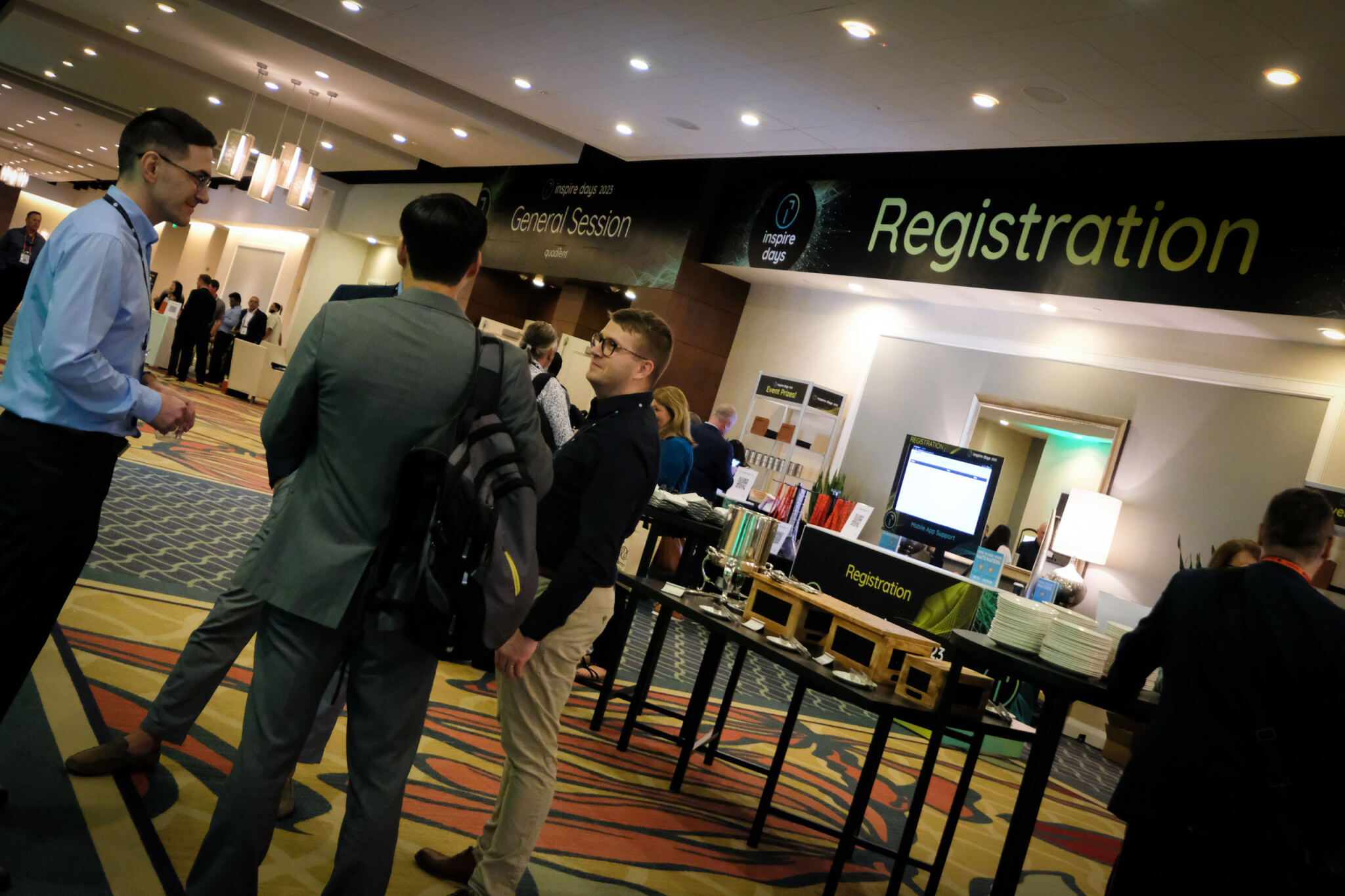 Attendees conversing near a registration desk at the Inspire Days 2023 General Session event.