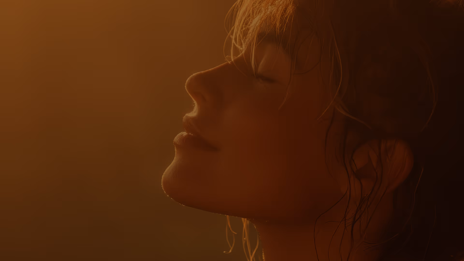 Image of a young woman with her eyers closed and smiling. The image has a warm tone.