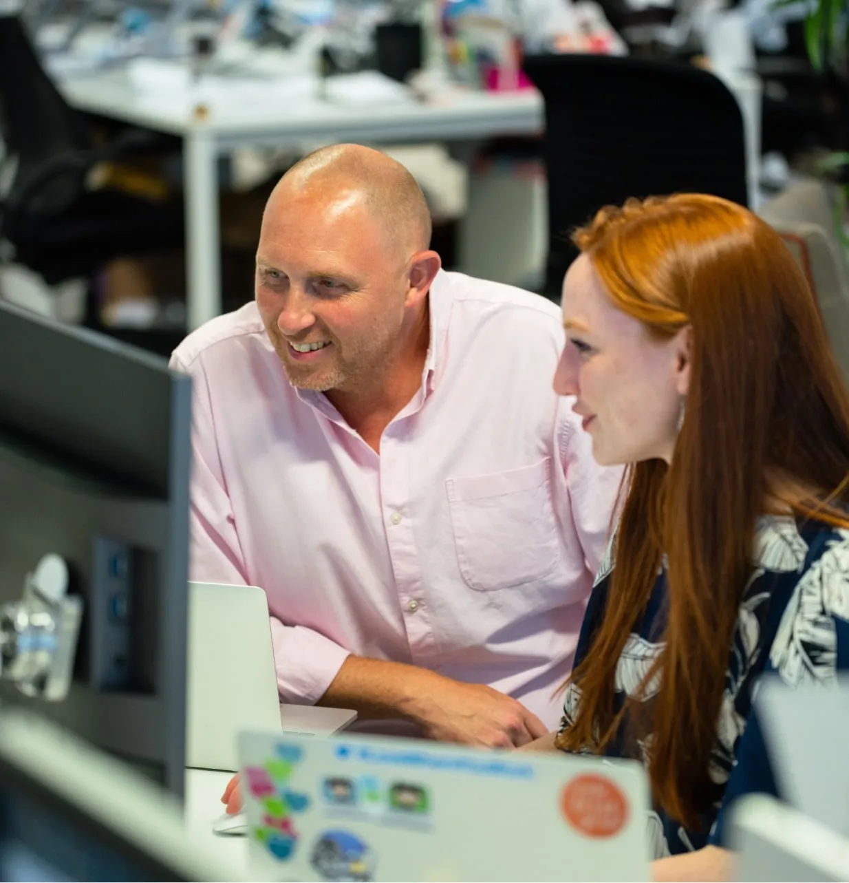 Two people are looking in to computer screen