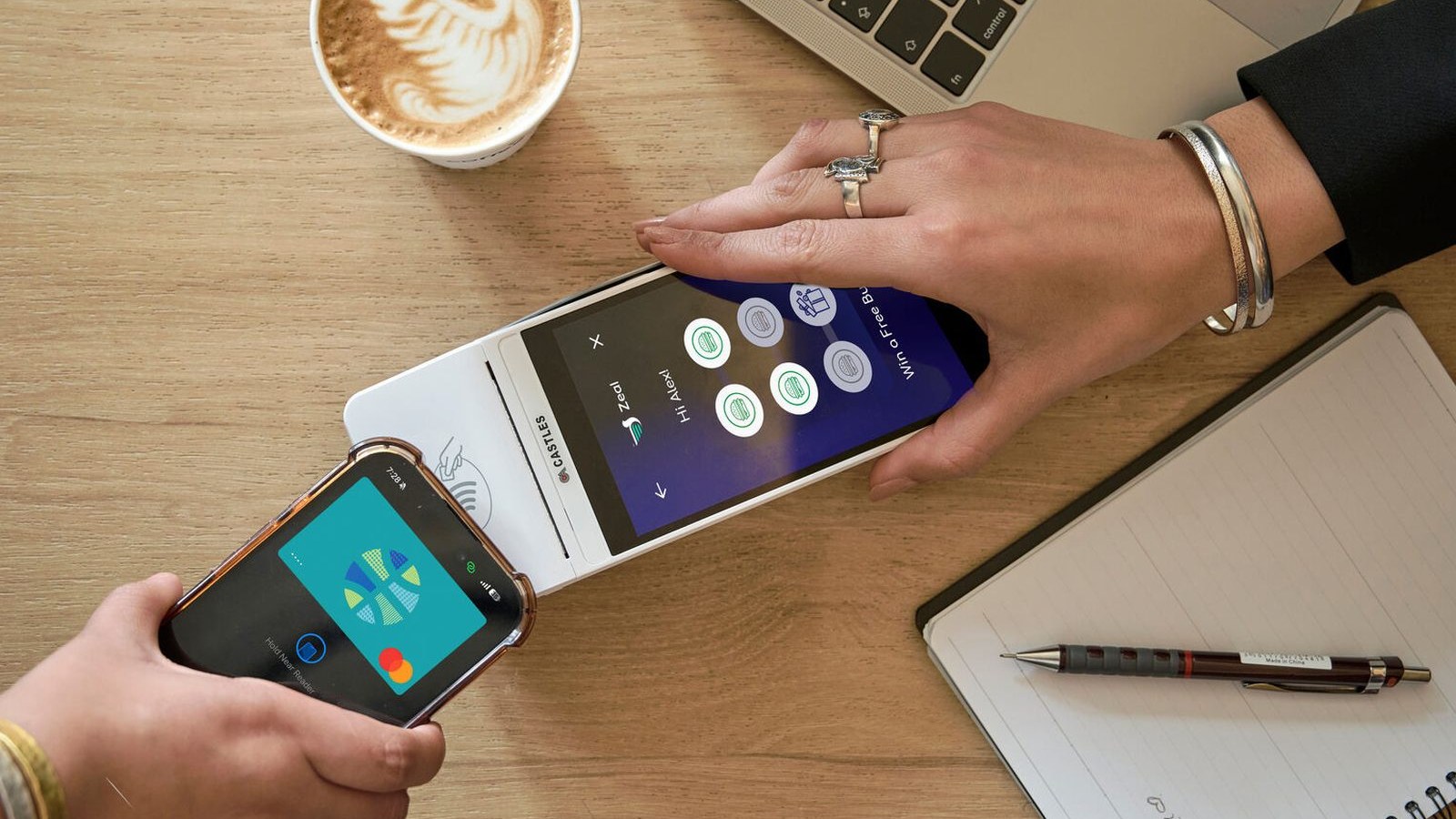 Contactless card payment on a terminal beside a coffee